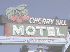 an old motel sign with cherries on it's top and the words cherry hill motel above it