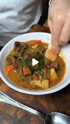 a person holding a spoon over a bowl of food