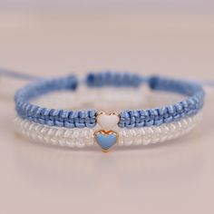 two blue and white beaded bracelets with a heart on the front, one in gold