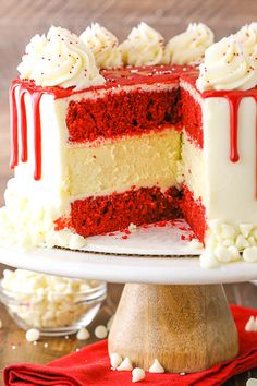 a red velvet layer cake with white frosting and sprinkles on top