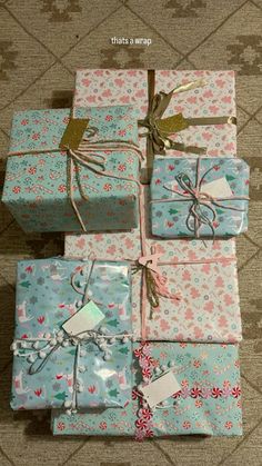 four wrapped presents sitting on top of each other in different colors and patterns, tied with twine