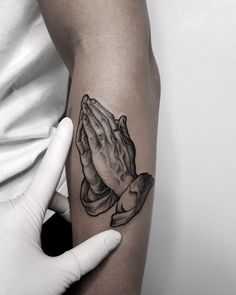 a person is holding their hands together with praying ink on the arm and hand behind them