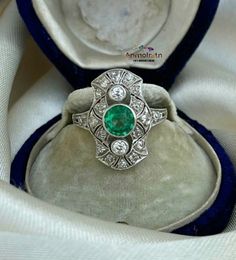 an old diamond and emerald ring in a velvet box