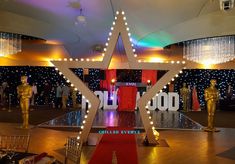 a red carpeted hall with statues and lights on the ceiling, in front of a large star