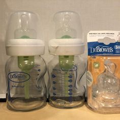 two baby bottles sitting on top of a counter next to a package of diapers