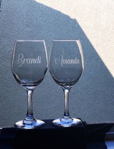 two wine glasses sitting side by side on a table with the words brandy and amanda written on them