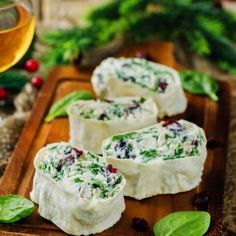 three pieces of appetizers on a wooden tray with holly wreaths in the background