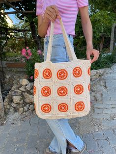 a woman is holding a crocheted bag with oranges on the front and sides