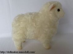 a white stuffed sheep is standing on a white tablecloth background and has black eyes