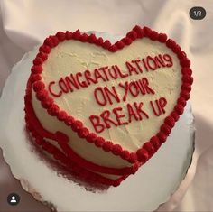 a heart shaped cake with congratulationss on your break up written in red and white frosting