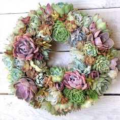 a wreath made out of succulents sitting on top of a wooden table