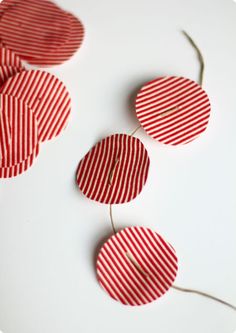 red and white striped paper circles are arranged on a white surface, with string attached to them