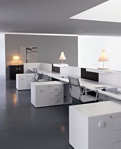 an office with white desks and two lamps on each side of the desk,