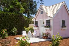 a small pink house with potted plants on the porch