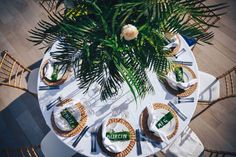 an overhead view of a table set with plates and napkins, palm tree leaves