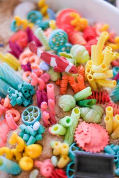 there are many different colored toys in the sand and on the ground, all together