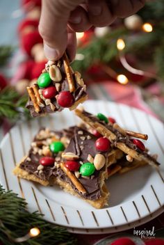 someone is holding up some christmas pretzels on a white plate with green and red candy