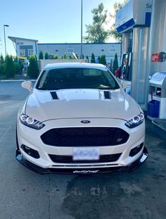 a white car parked in front of a gas station