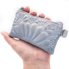 a woman's hand holding a silver purse