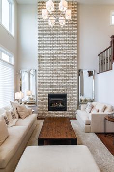 a living room with white couches and a fire place in the middle of it