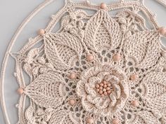 a crocheted doily with a flower on the center and beading around it