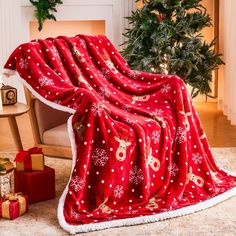 a red christmas blanket with white snowflakes and reindeers on it next to presents