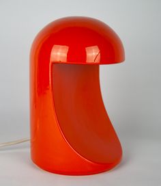 an orange table lamp sitting on top of a white surface