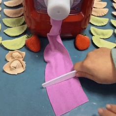 someone is making something out of paper on the table with strawberries and other things