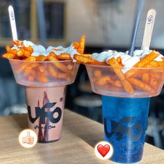 two cups filled with food sitting on top of a wooden table next to each other