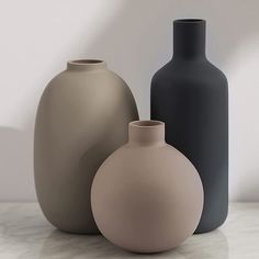 three different colored vases sitting on top of a white table next to each other