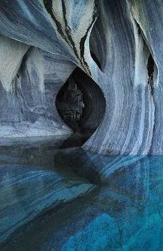 the water is very blue and clear in this cave like area that looks like it has been carved into an iceberg