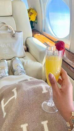 a person holding a wine glass in their hand while sitting on an airplane with the window open