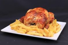 a white plate topped with chicken and french fries on top of a black tablecloth