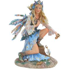 a figurine of a woman dressed as a fairy sitting on top of a tree stump