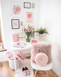 a white desk topped with a pink chair next to a potted plant and flowers