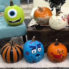 pumpkins with faces painted on them sitting in front of a blue chair