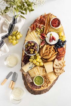 a platter with cheeses, crackers, grapes and other foods on it