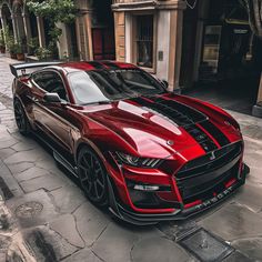 a red sports car parked on the side of a street next to a tall building