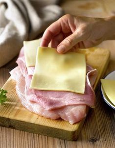 a person cutting up meat on top of a wooden cutting board