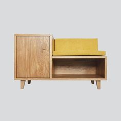 a wooden cabinet with a yellow cushion on it's top and bottom, sitting next to a gray wall