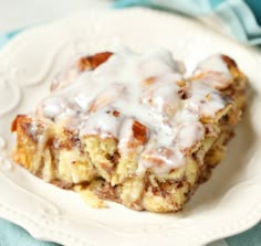 a white plate topped with cinnamon rolls covered in icing on top of a blue and white table cloth