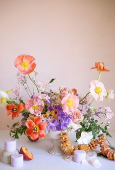 a white vase filled with lots of flowers on top of a table next to candles