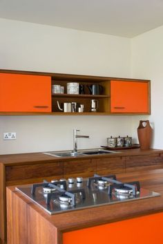 an orange kitchen with wooden cabinets and stainless steel stove top burners, in a home