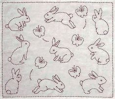 a white table cloth with small embroidered rabbits on the front and back of it,