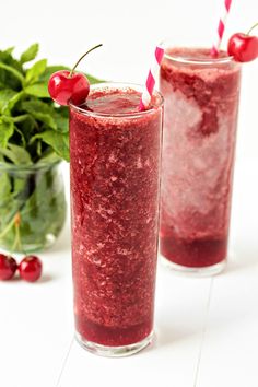 two glasses filled with smoothie and garnished with cherries