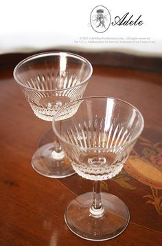 two clear wine glasses sitting on top of a wooden table