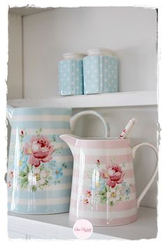 two pink and blue flowered pitchers sitting on top of a shelf