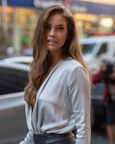 a woman with long hair standing on the street