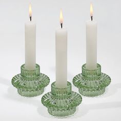 three green glass candle holders with white candles