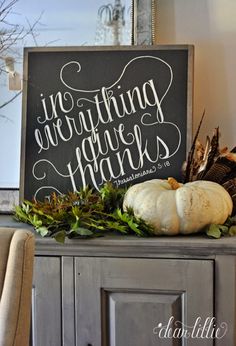 a chalkboard sign sitting on top of a wooden cabinet next to a chair and window